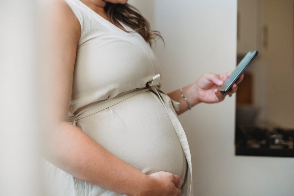 pregnant woman cradling her belly and holding her mobile phone