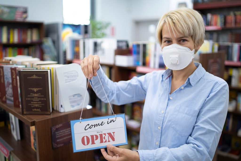 LIbrarian holding a "we're open" sign