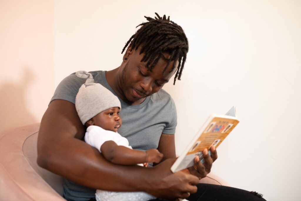 Man holding a baby as they read a book