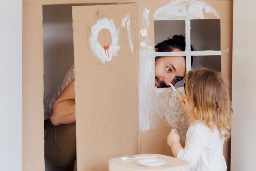 Man behind a cardboard window and girl pinting the cardboard white